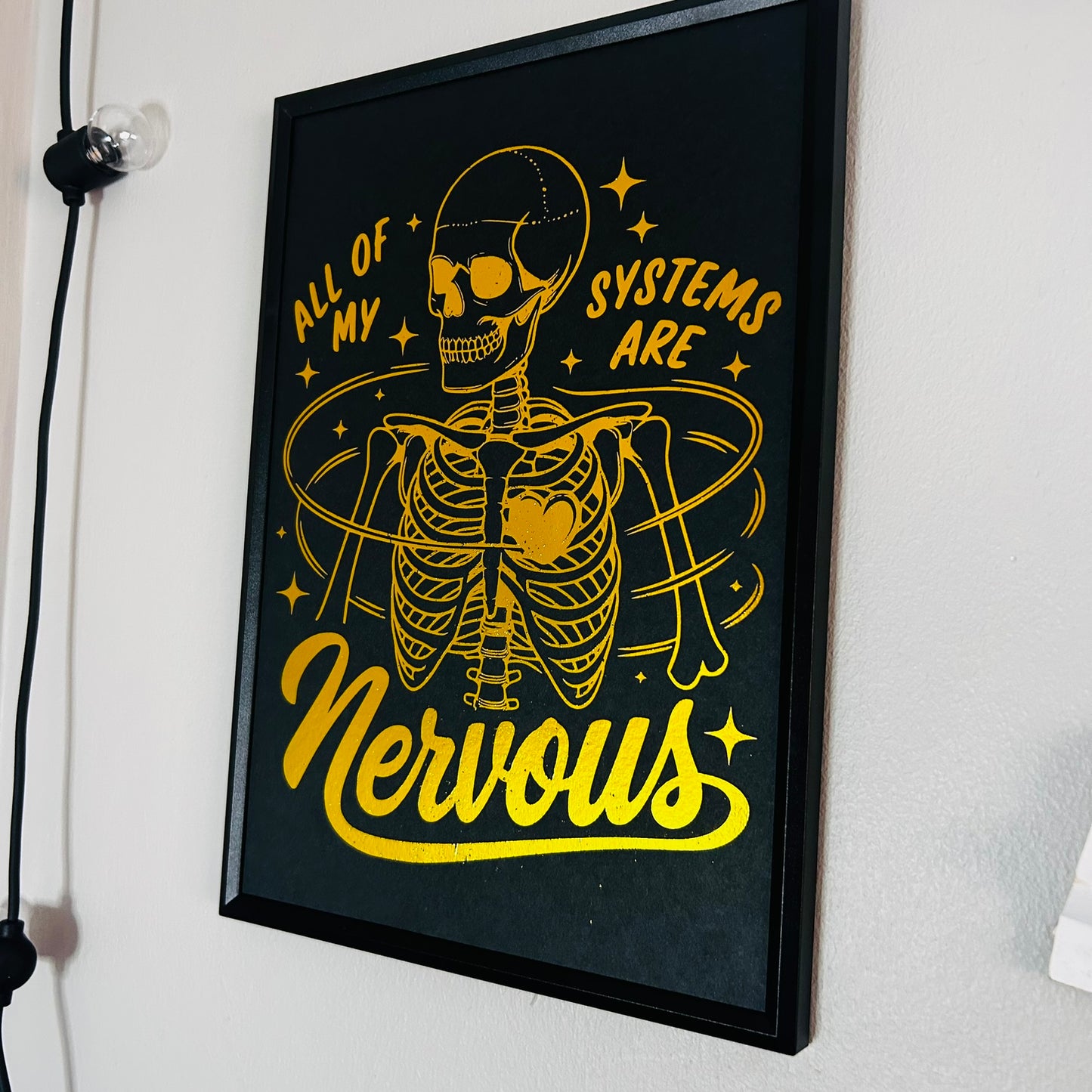 Framed artwork with a yellow skeleton design and text on a black background