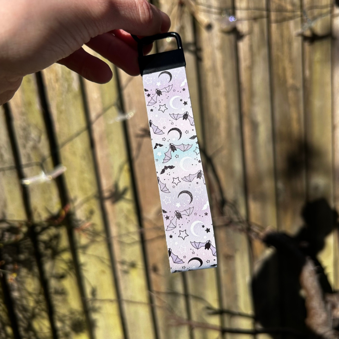 Pastle blue and pink wristlet with bat and moon design with black hardware